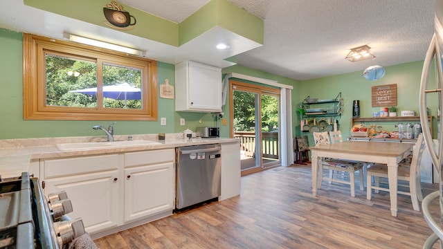 kitchen with white cabinets, light hardwood / wood-style flooring, stainless steel appliances, sink, and a textured ceiling