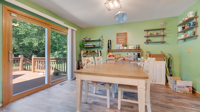 dining space with a textured ceiling and light hardwood / wood-style flooring