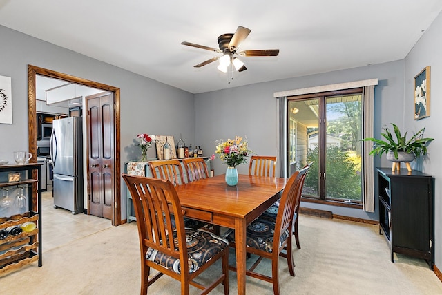 dining area featuring ceiling fan and light colored carpet