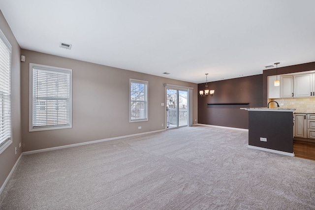 unfurnished living room featuring carpet floors and a chandelier