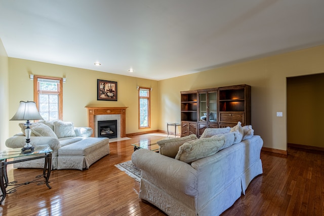 living room featuring a tiled fireplace and dark hardwood / wood-style flooring