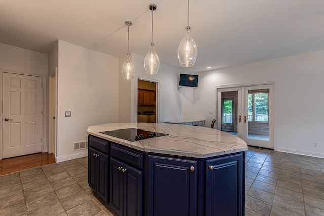 kitchen featuring decorative light fixtures, a center island, washing machine and dryer, black electric cooktop, and light stone counters