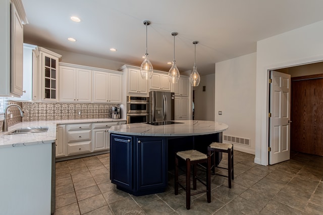 kitchen featuring a kitchen island, stainless steel appliances, sink, white cabinetry, and light stone counters