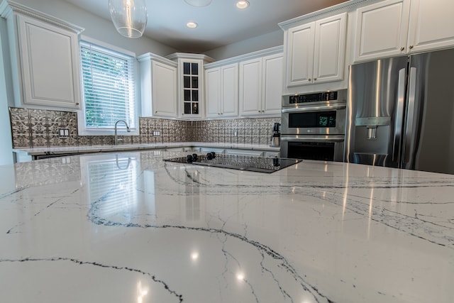 kitchen with stainless steel appliances, sink, decorative backsplash, light stone counters, and white cabinets