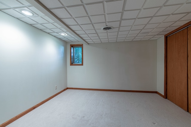 interior space featuring a paneled ceiling and light colored carpet