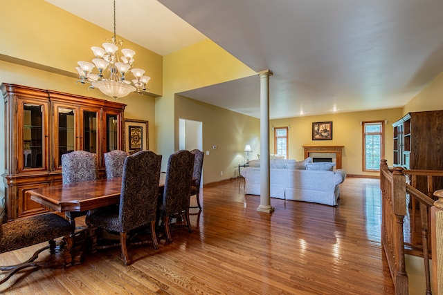 dining space featuring hardwood / wood-style floors, ornate columns, and a notable chandelier