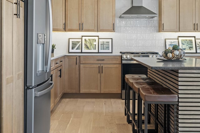 kitchen featuring wall chimney exhaust hood, tasteful backsplash, stainless steel appliances, and light wood-type flooring