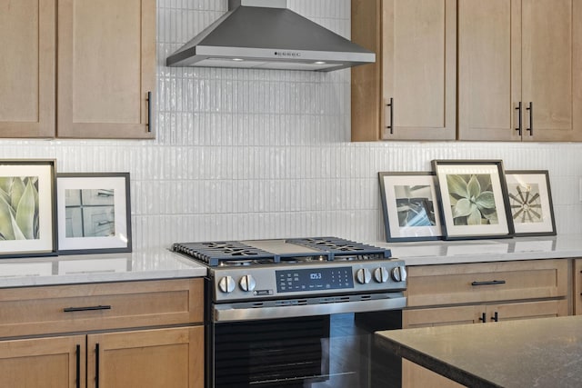 kitchen with decorative backsplash, wall chimney exhaust hood, dark stone countertops, and stainless steel gas range oven