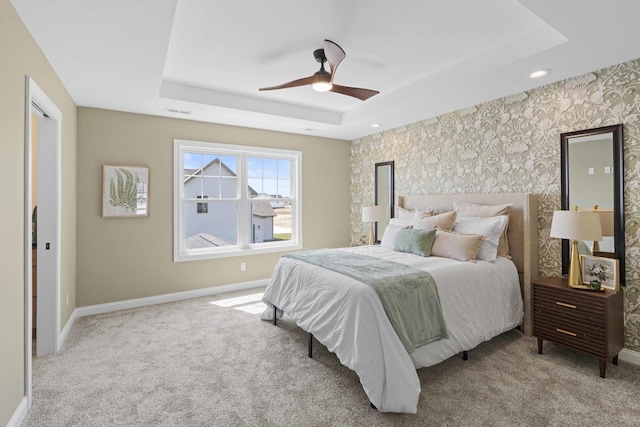carpeted bedroom featuring visible vents, baseboards, wallpapered walls, ceiling fan, and a raised ceiling