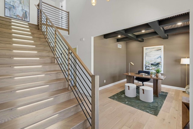 interior space featuring coffered ceiling, beam ceiling, wood finished floors, and baseboards