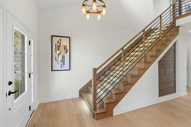 foyer featuring stairway, a notable chandelier, baseboards, and wood finished floors