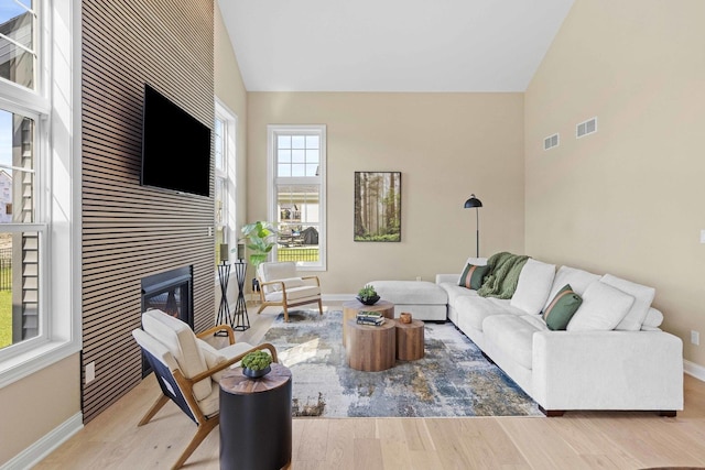 living area featuring wood finished floors, baseboards, a tiled fireplace, and visible vents