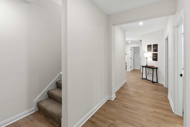 corridor featuring recessed lighting, baseboards, light wood-style floors, and stairs