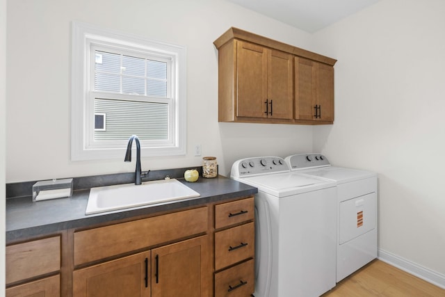 laundry room with cabinet space, light wood-type flooring, a sink, and separate washer and dryer