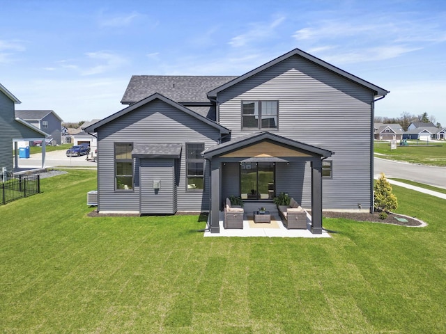 rear view of house featuring a yard, a patio area, a shingled roof, and fence