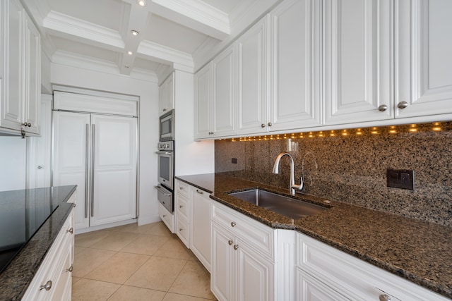 kitchen with white cabinetry, sink, beamed ceiling, built in appliances, and dark stone countertops