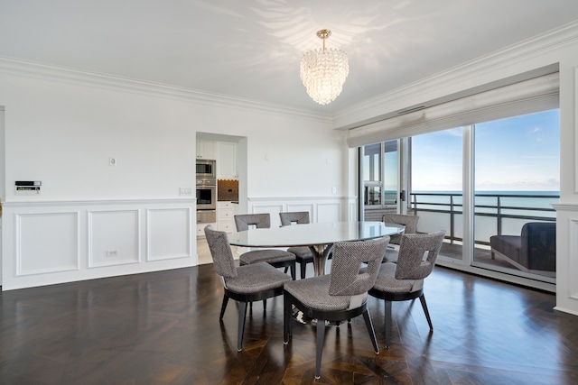 dining area featuring a notable chandelier, a water view, ornamental molding, and dark parquet flooring