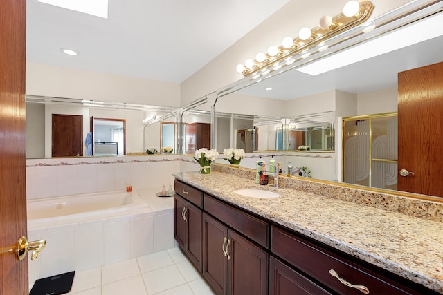 bathroom with tile patterned floors, a skylight, separate shower and tub, and vanity