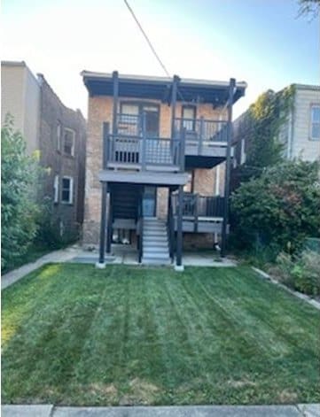 rear view of house featuring a lawn and a balcony