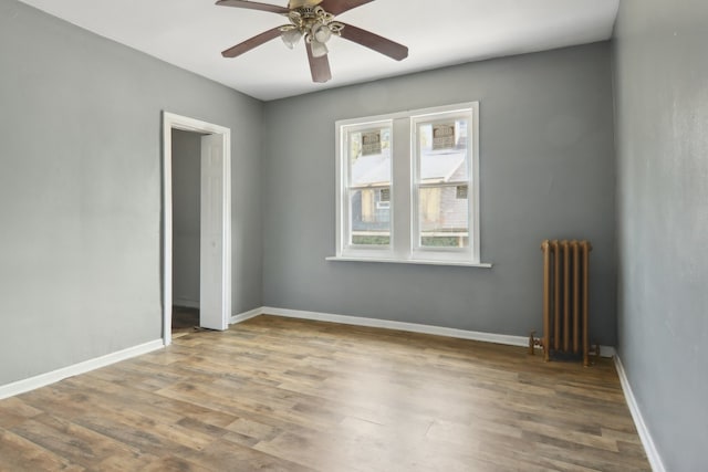 unfurnished room with ceiling fan, radiator heating unit, and hardwood / wood-style flooring