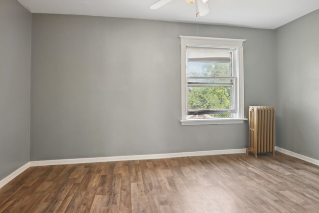 empty room with ceiling fan, radiator heating unit, and wood-type flooring