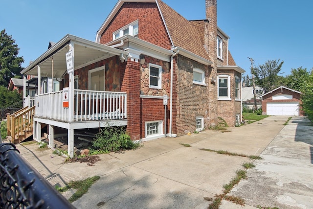 view of side of property with a porch, a garage, and an outdoor structure