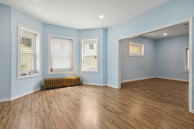 unfurnished living room with radiator and wood-type flooring