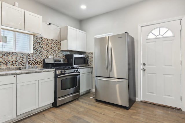 kitchen featuring stainless steel appliances, wood-type flooring, and white cabinets