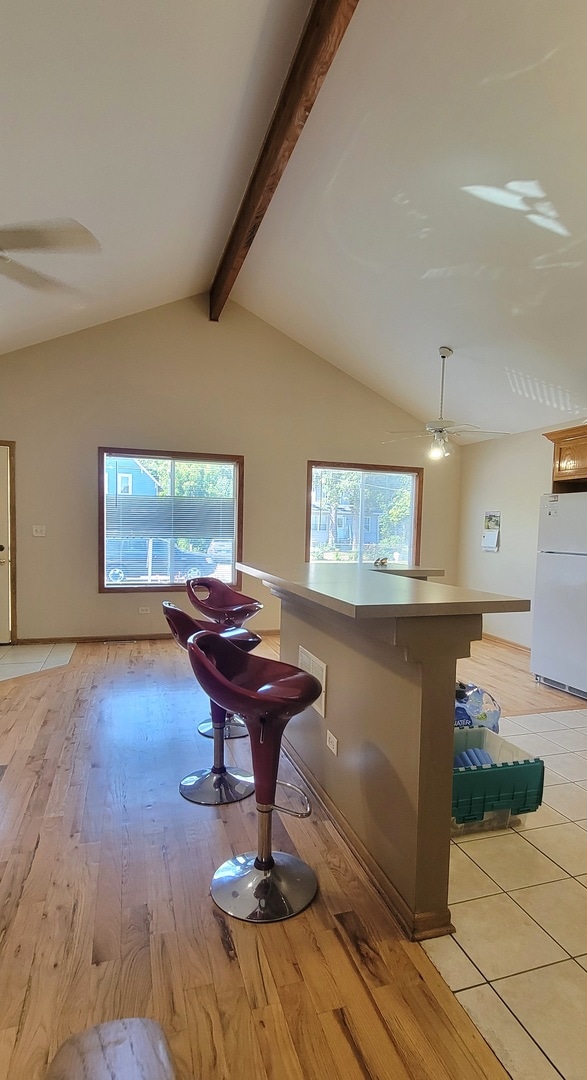 interior space with a wealth of natural light, a breakfast bar area, white refrigerator, and light wood-type flooring