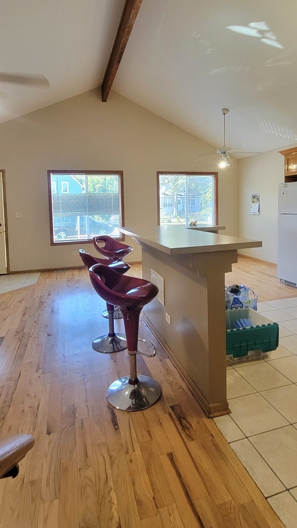 kitchen with a breakfast bar area, white fridge, and light wood-type flooring