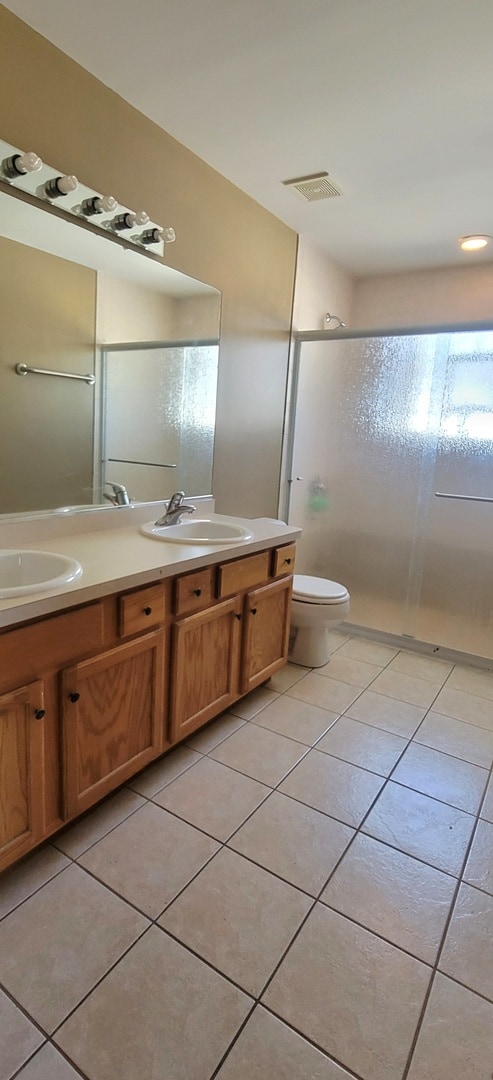 bathroom with vanity, toilet, tile patterned floors, and walk in shower