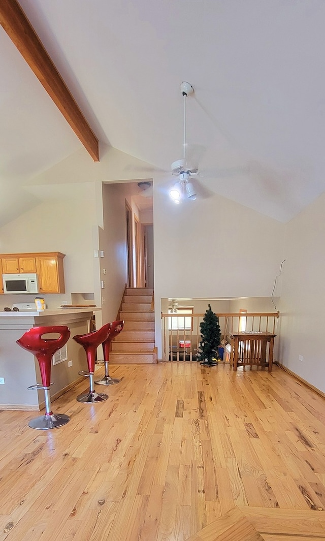 interior space featuring light wood-type flooring, ceiling fan, high vaulted ceiling, and beamed ceiling