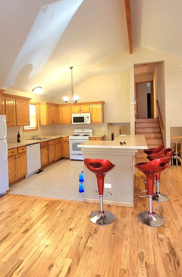 kitchen with light wood-type flooring, white appliances, decorative light fixtures, lofted ceiling with beams, and a breakfast bar area