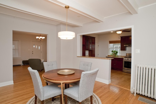 dining area featuring beam ceiling, radiator heating unit, and light hardwood / wood-style floors