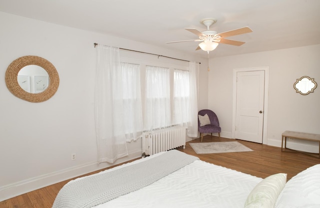 bedroom with ceiling fan, radiator heating unit, and wood-type flooring