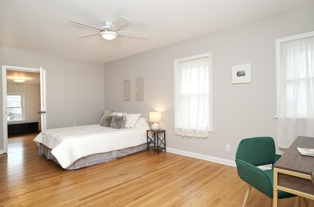 bedroom with radiator heating unit, ceiling fan, and light wood-type flooring