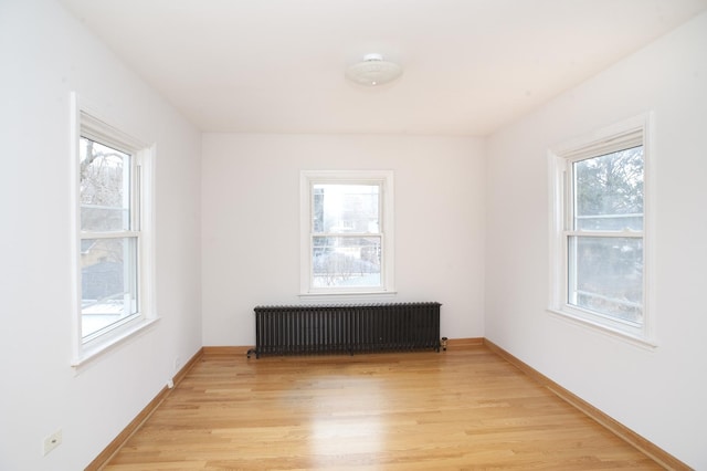 unfurnished room with radiator heating unit and light hardwood / wood-style floors