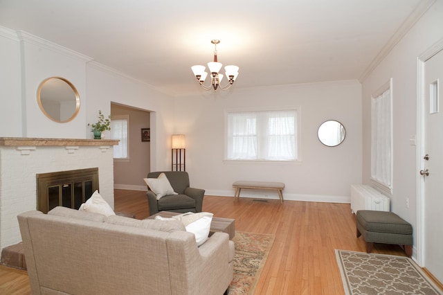 living room featuring crown molding, radiator, a brick fireplace, and light wood-type flooring