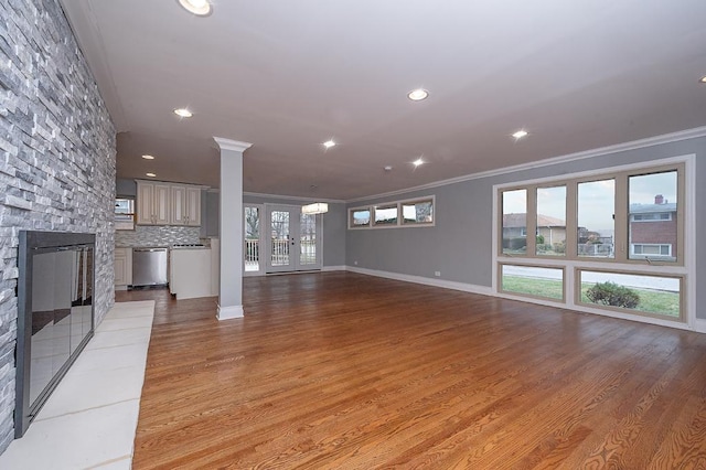 unfurnished living room with french doors, crown molding, a fireplace, and light hardwood / wood-style floors