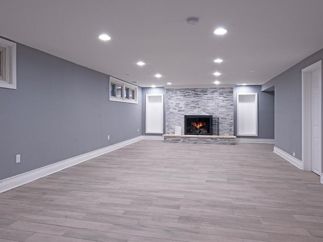 unfurnished living room featuring a stone fireplace and light wood-type flooring