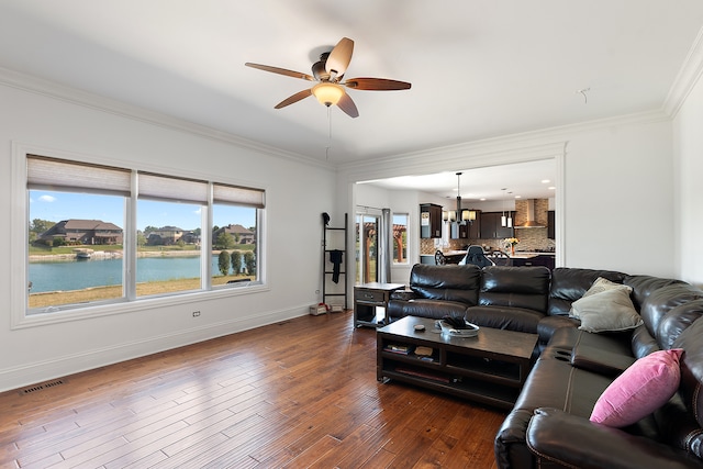 living room with crown molding, dark hardwood / wood-style floors, ceiling fan with notable chandelier, and a water view