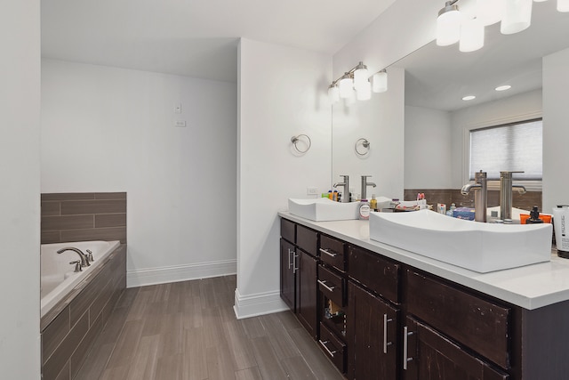 bathroom featuring tiled bath, vanity, and wood-type flooring