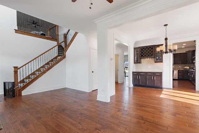 unfurnished living room with ceiling fan with notable chandelier, dark hardwood / wood-style flooring, and ornamental molding