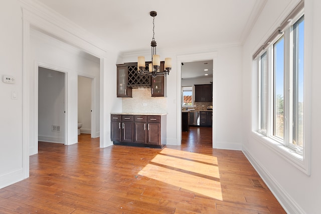 unfurnished living room with ornamental molding, hardwood / wood-style floors, and a notable chandelier