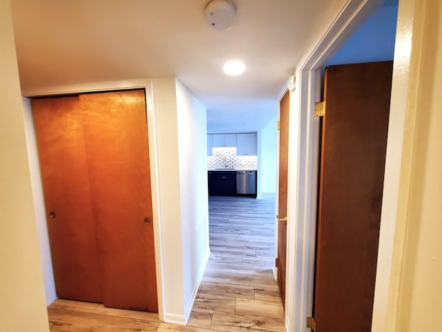 corridor with light hardwood / wood-style floors and sink