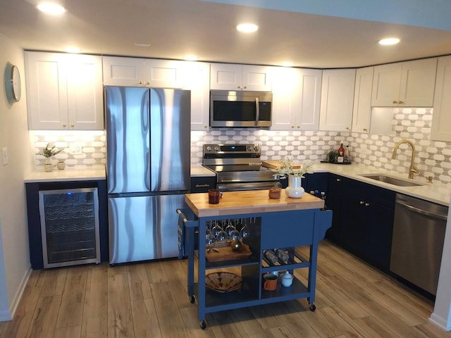 kitchen with white cabinets, wine cooler, sink, and appliances with stainless steel finishes