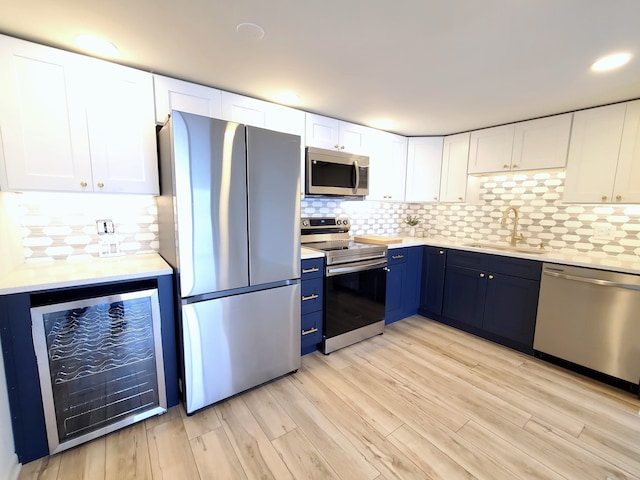 kitchen featuring white cabinets, light hardwood / wood-style floors, stainless steel appliances, and beverage cooler