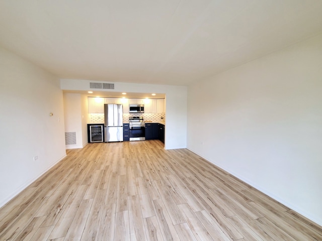 unfurnished living room with light hardwood / wood-style floors and beverage cooler