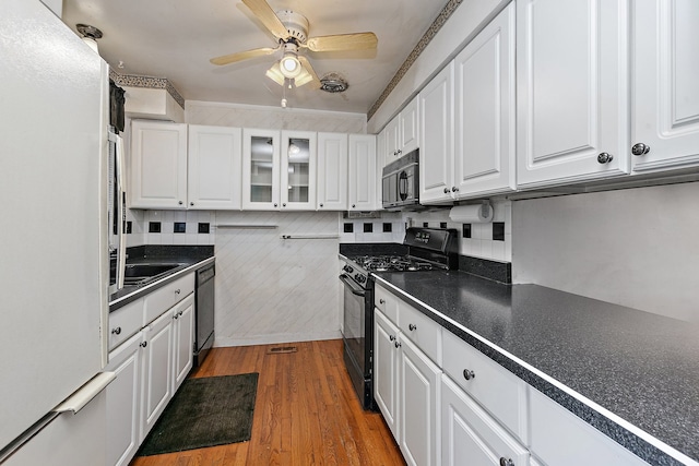 kitchen featuring wood-type flooring, white cabinetry, decorative backsplash, and black appliances