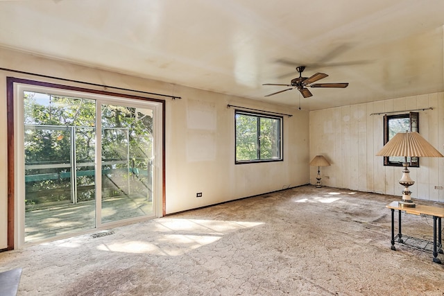 unfurnished living room featuring carpet flooring, ceiling fan, and a wealth of natural light